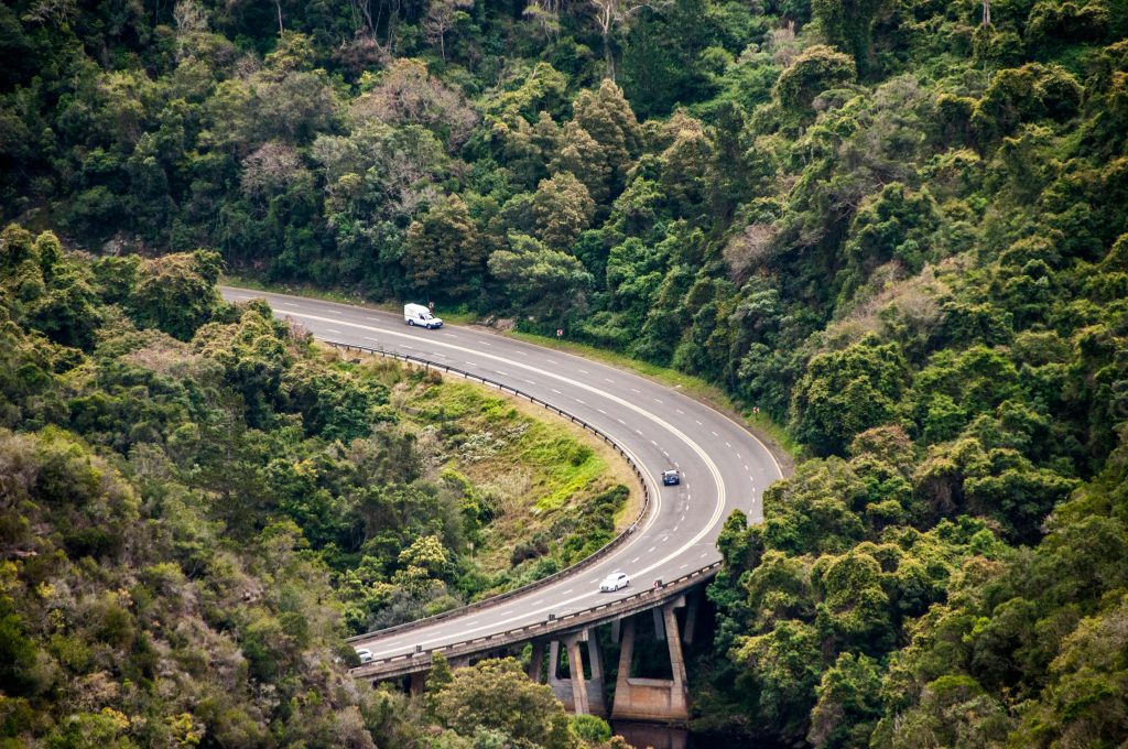 Aerial shot of a curving mountain road surrounded by lush forest in George, Western Cape.
